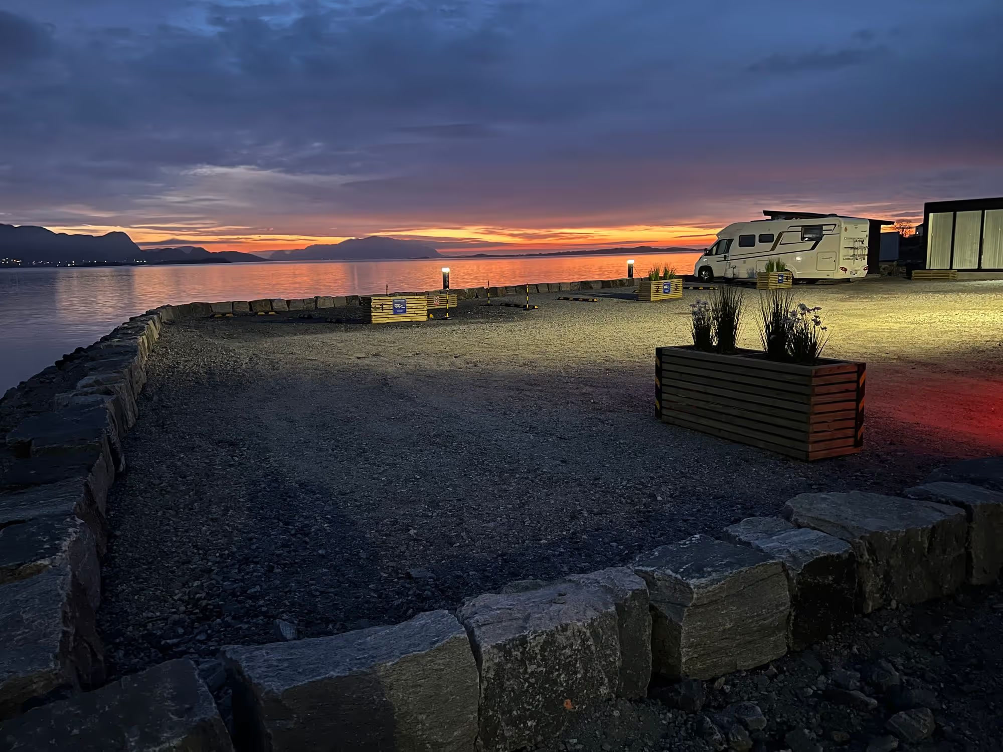 Sjøfronten Bobilpark i solnedgang, med bobil ved fjorden