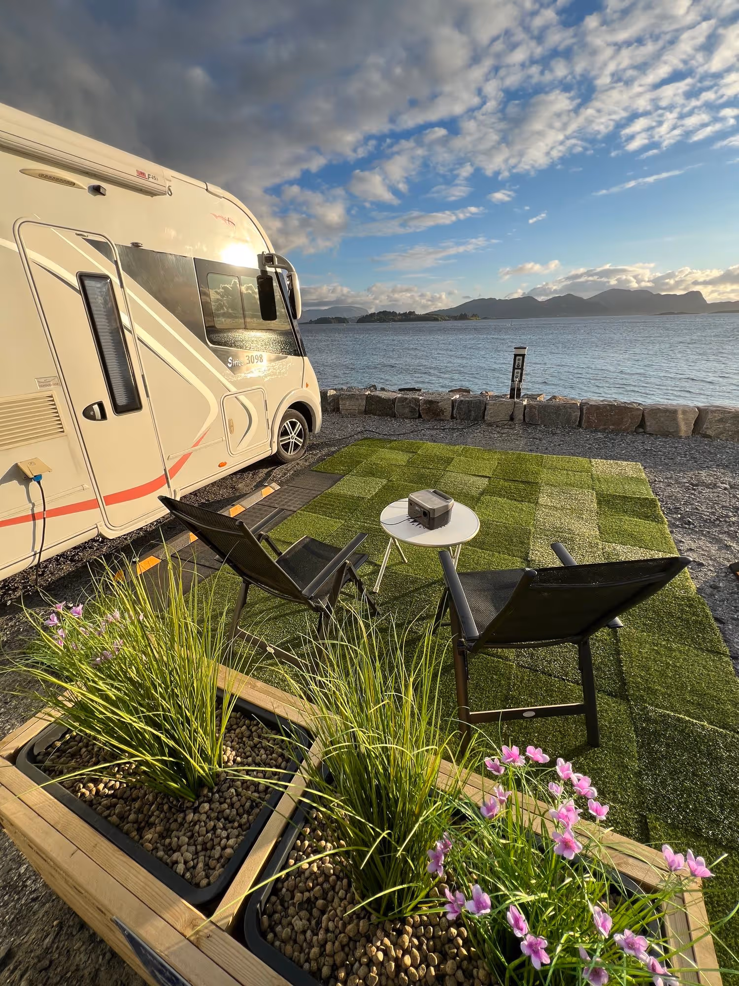Sitteplass på kunstgress ved en bobil og fjorden