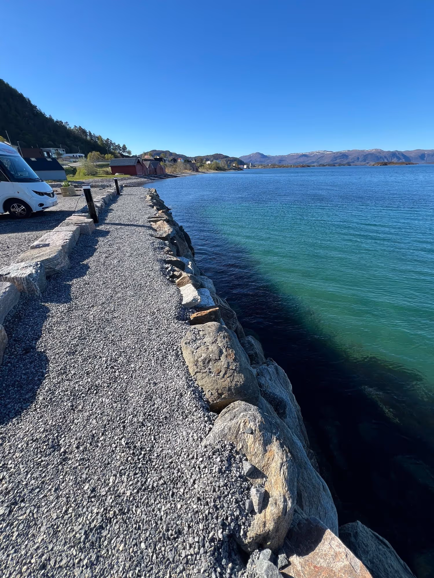 Gangsti langs den klare fjorden ved bobilplassen